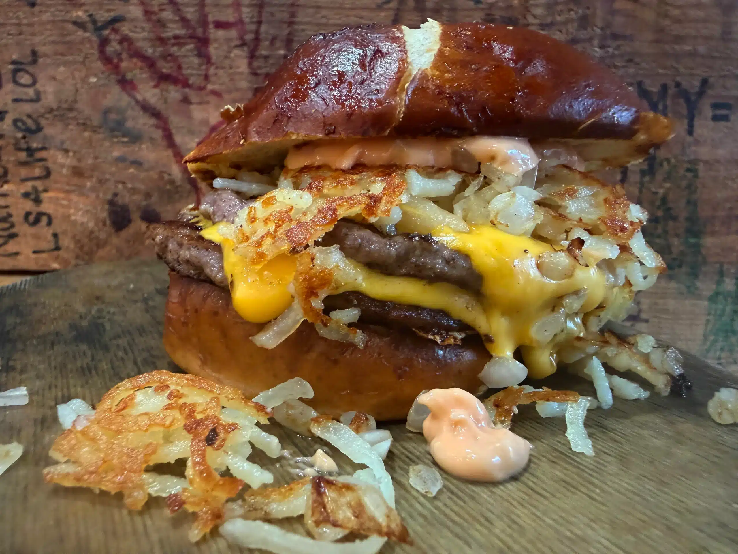 Cease and Desist Burger 2.0 with double smashed patties, chopped grilled onion, Sha'1000 island dressing, hash browns, and American cheese on a pretzel bun.