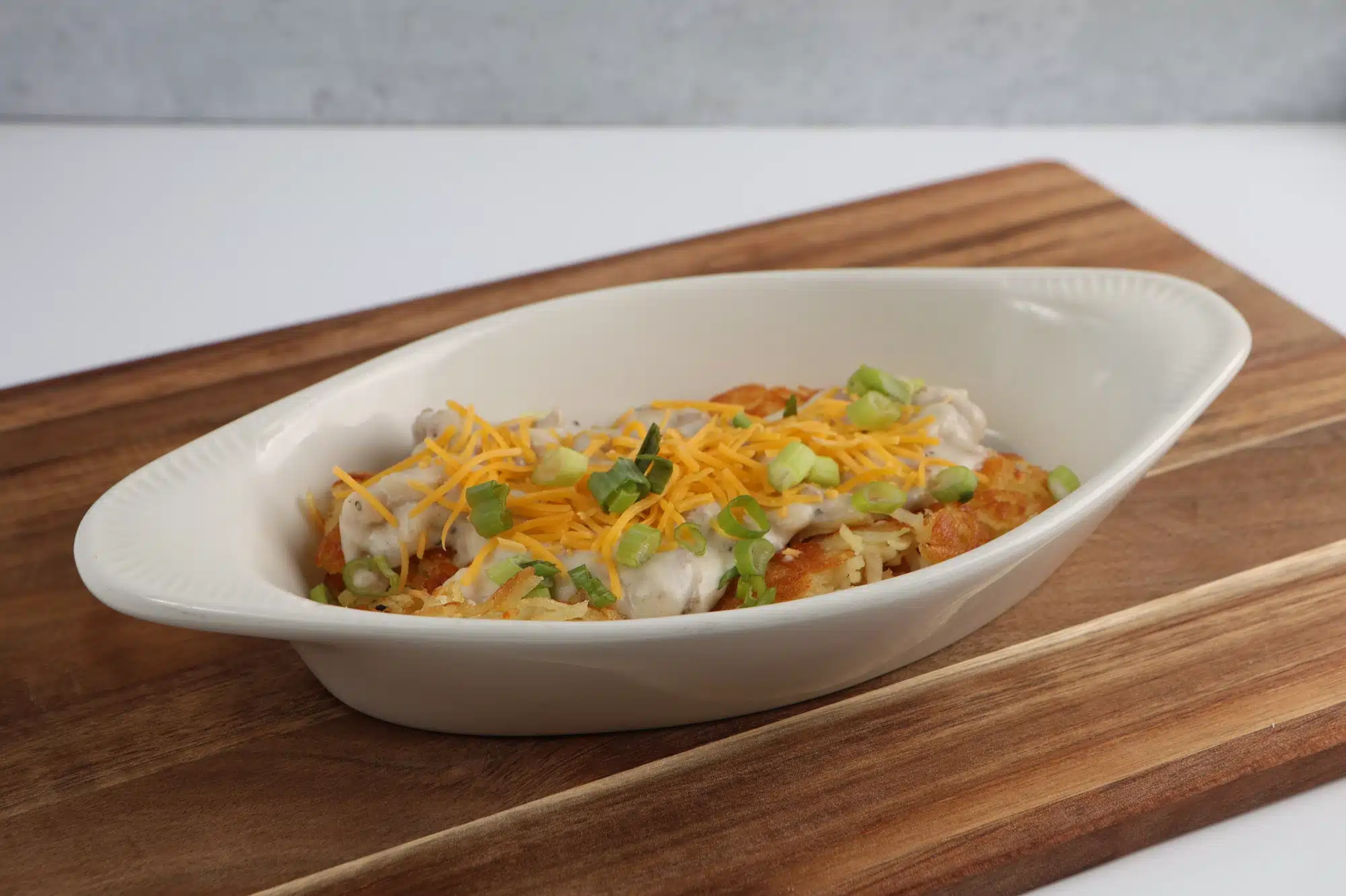 Hash browns topped with sausage gravy, shredded cheddar cheese, and sliced green onions.