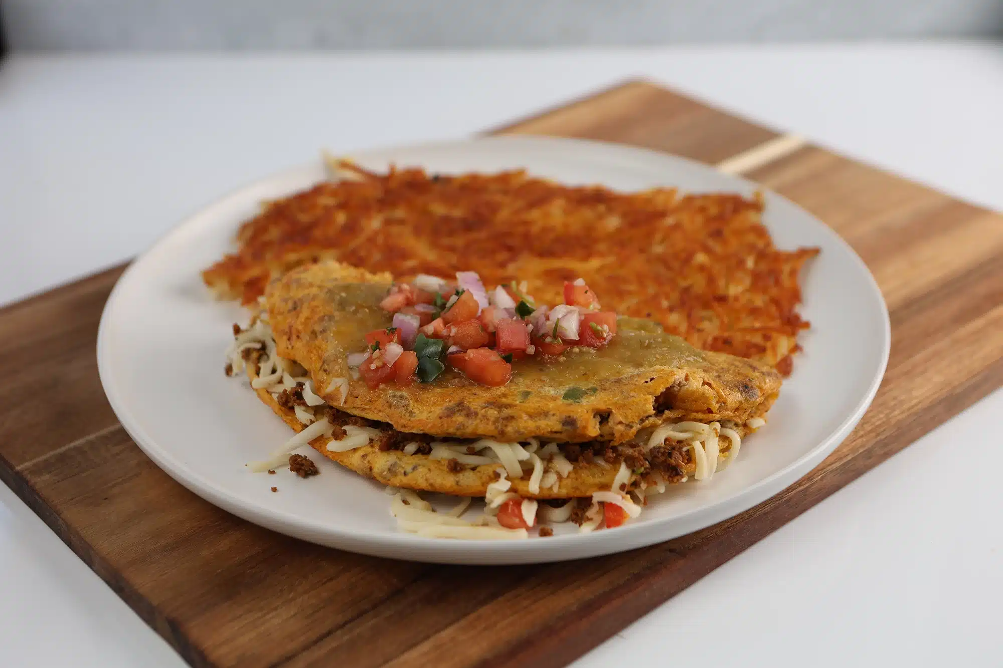 Folded chorizo and cheese omelet topped with salsa verde and pico de gallo, served with hash browns.