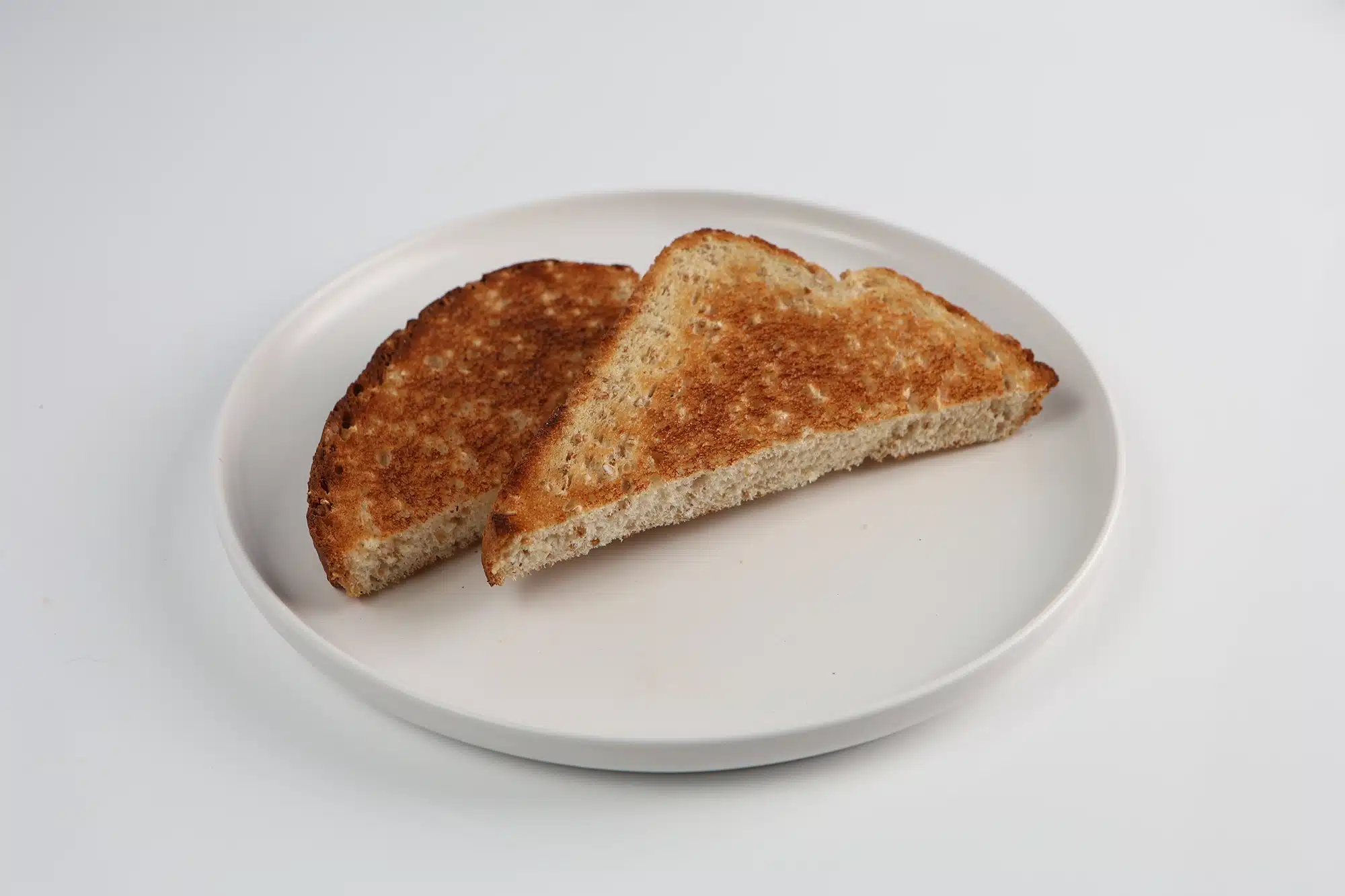 Two triangle-cut halves of golden brown toast on a white plate.