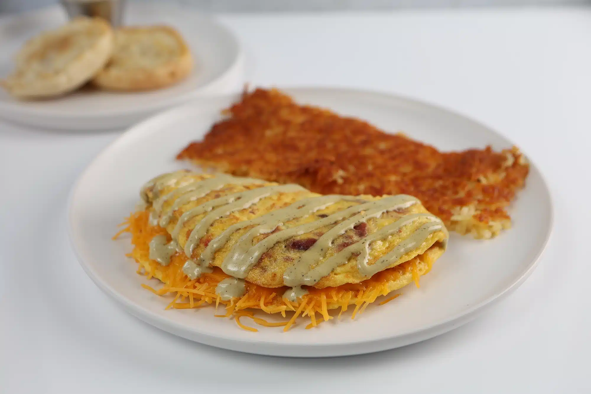 Folded bacon and cheddar omelet drizzled with ranch dressing, served over shredded cheddar with a side of hash browns.