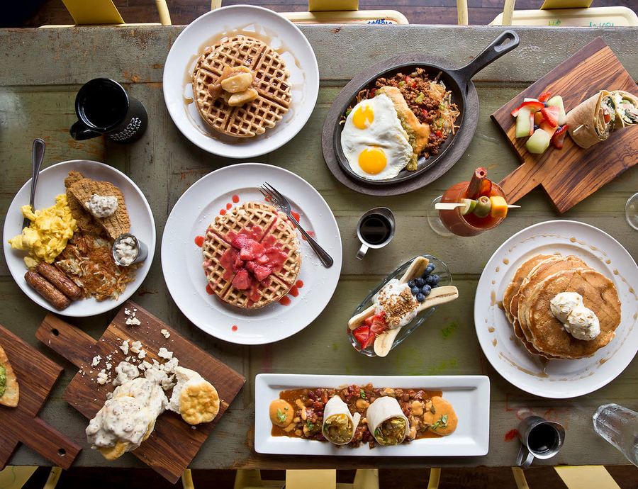 An overhead Shack table spread with waffles, skillets, biscuits and gravy, burritos and coffee.
